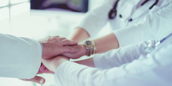Doctors and nurses in a medical team stacking hands.