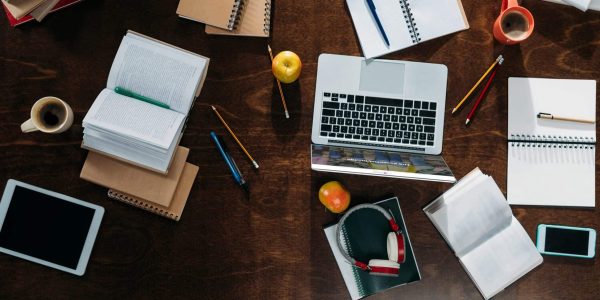 top view of digital devices with notebooks and coffee cups with apples on tabletop
